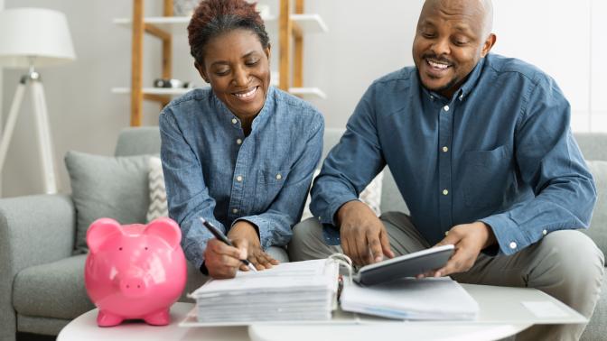 A couple filling out forms with a piggy back on the table