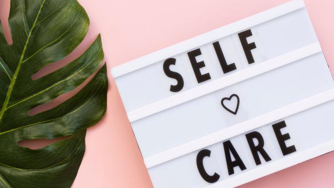 A sign next to a plant that says self care