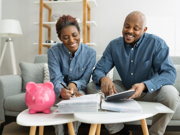 A couple filling out forms with a piggy back on the table