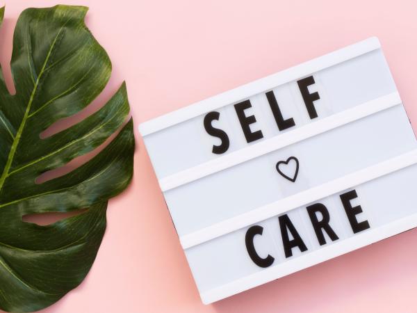 A sign next to a plant that says self care