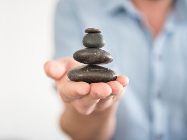 Someone balances a small tower of smooth rocks in their hand