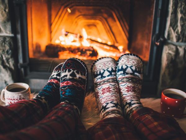 Two people in cozy knit socks warming up by a fireplace