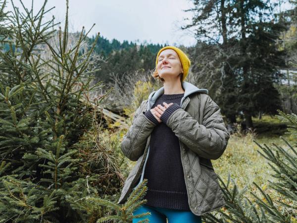A woman taking a deep breath in the forest